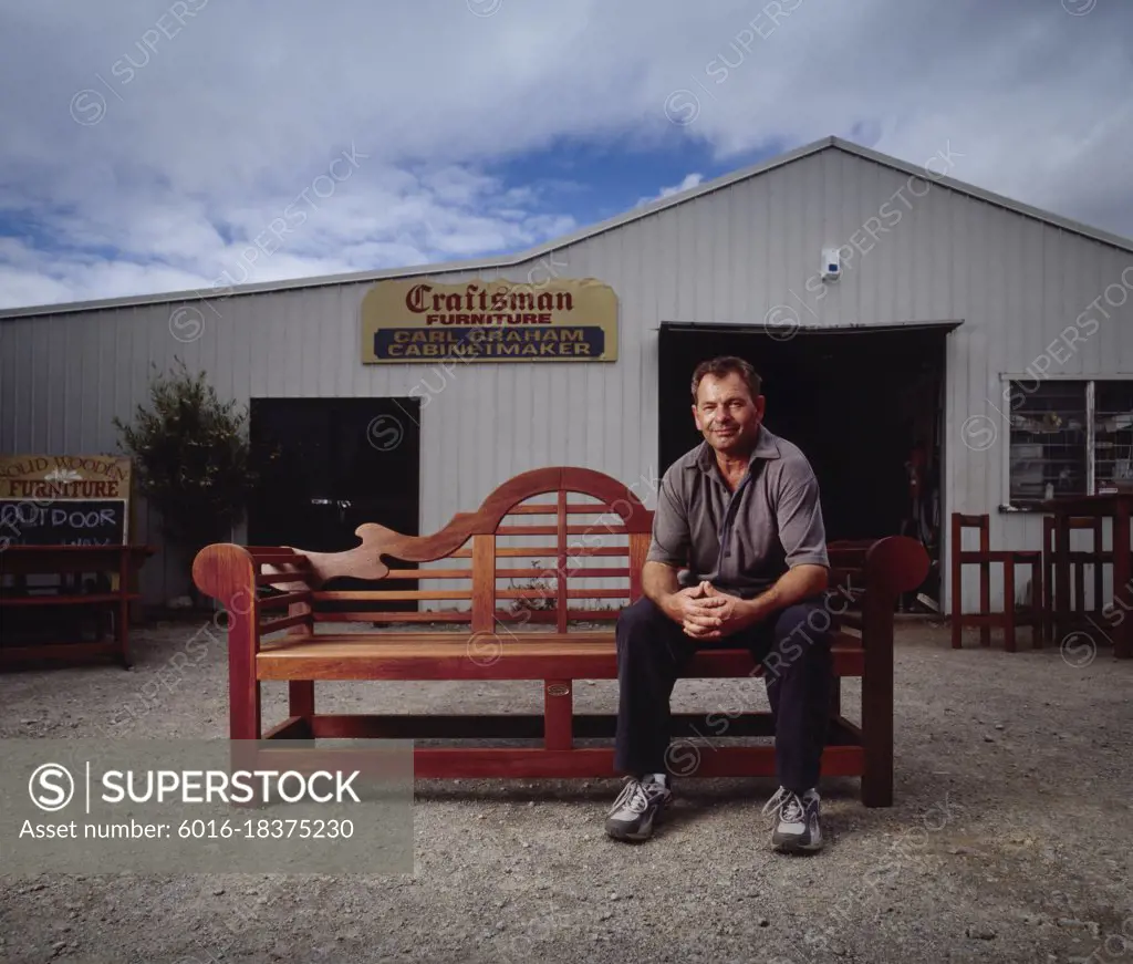 Portrait of cabinetmaker sitting on outside seat in front of his business