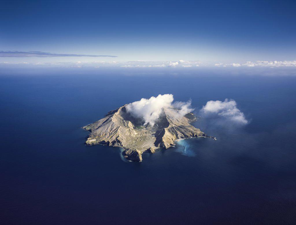 Aerial of Whiste Island active Volcano smoking in the middle of blue ocean