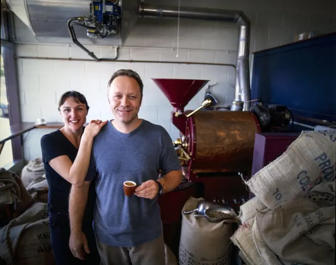 Portrait of coffee master roasters sampling cup of coffee in roasting room