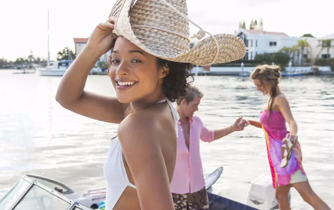Young woman with straw sunhat smiling and couple boarding boat on cannal