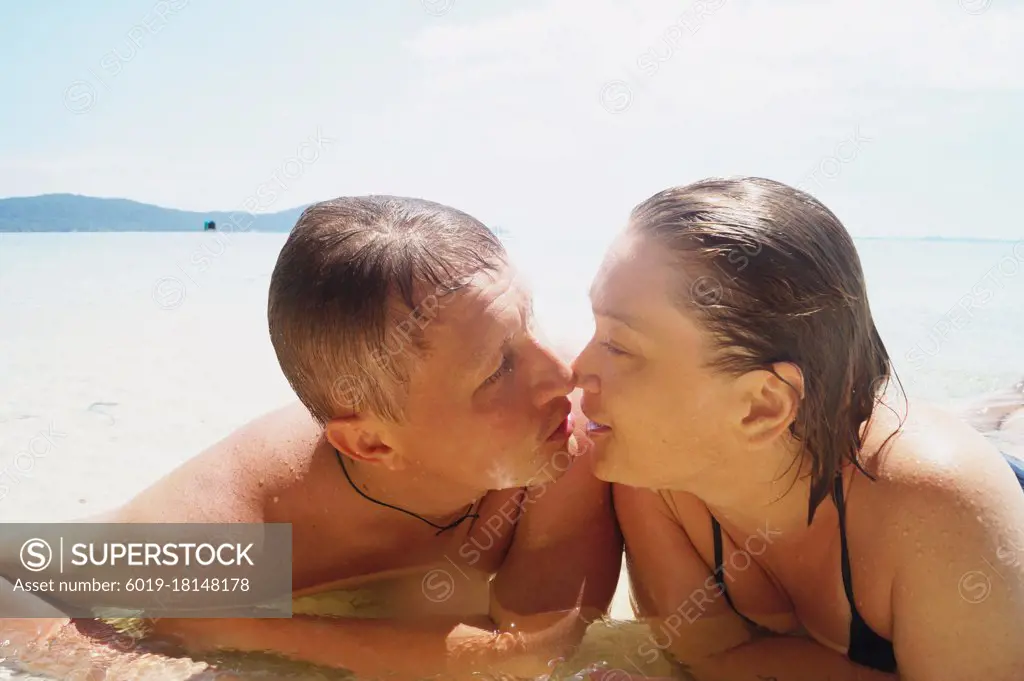 Husband and wife kiss on the beach