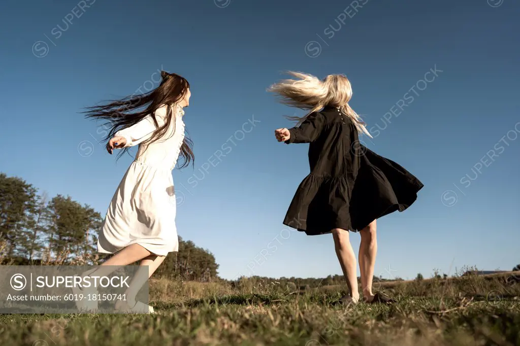two beautiful twin girls doing style lying in a field at sunset