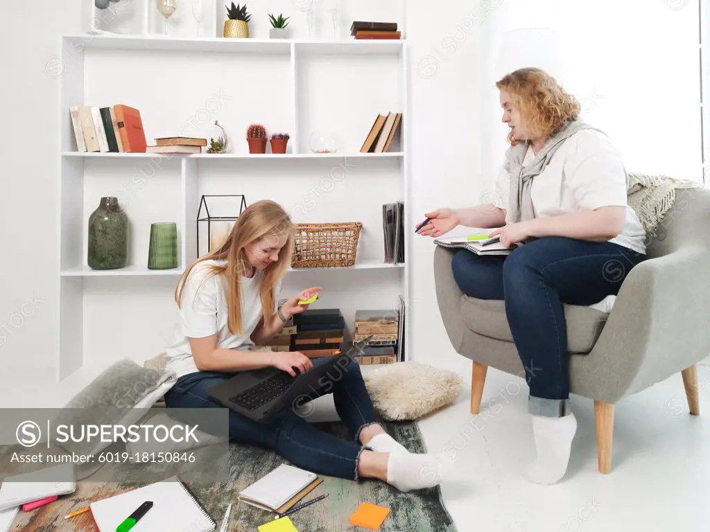 two blond women studying at home laptop and notebooks