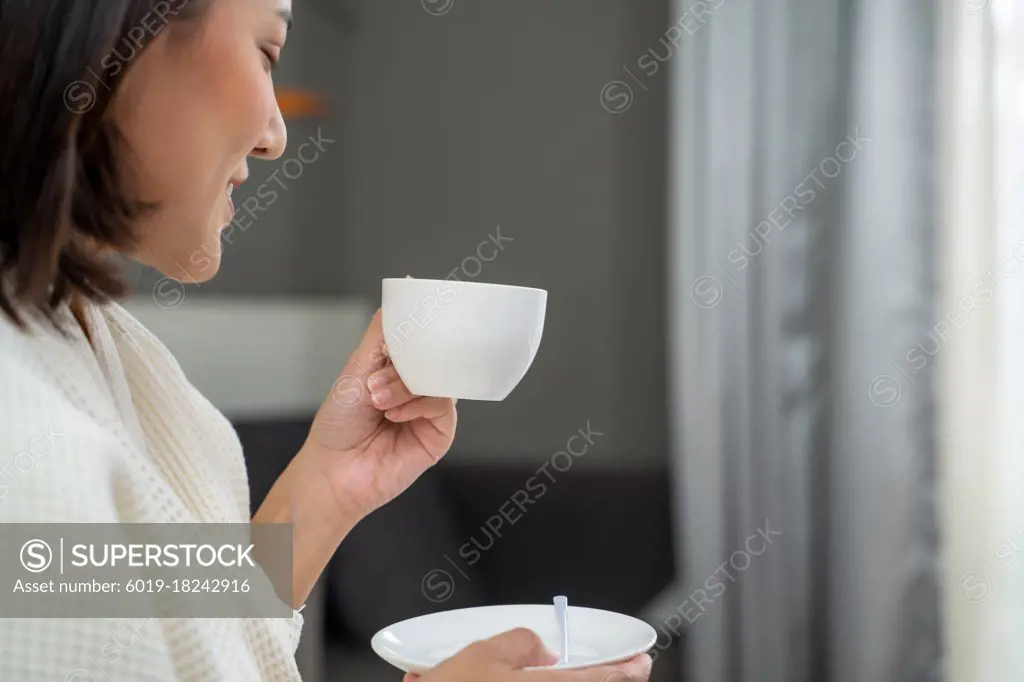 Portrait of beautiful woman having coffee on bed at hotel room