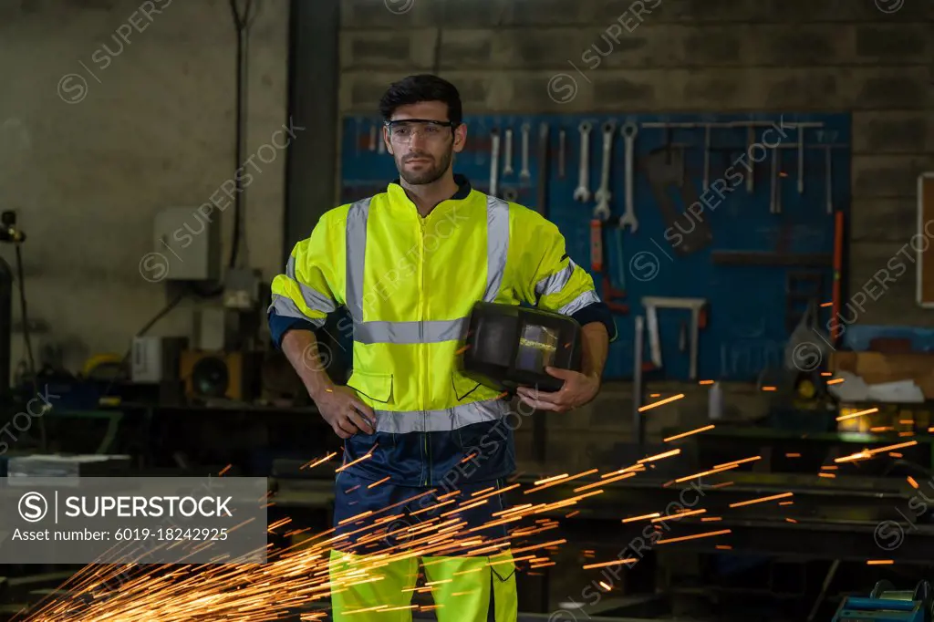 Industrial worker with many sharp sparks at factory