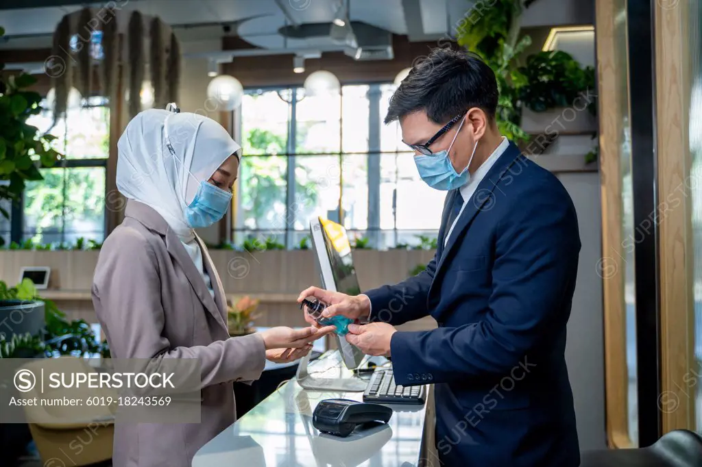 Business people with face mask are disinfecting hands