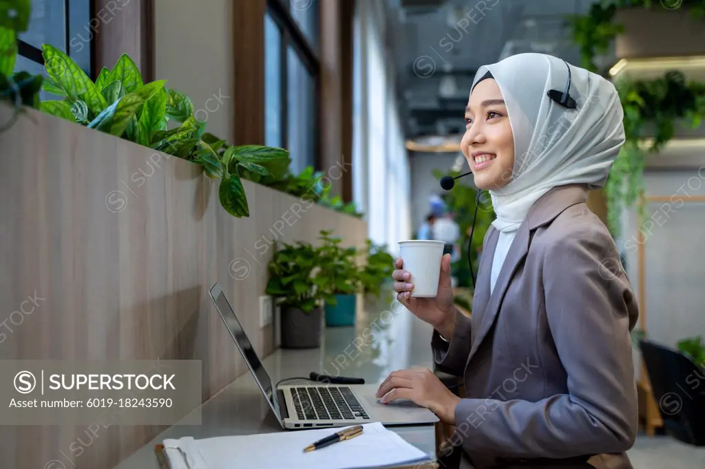 Asian Muslim women drink coffee before working in office
