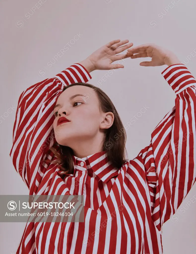 Fashion girl. Young brunette woman posing at studio in striped red and white shirt white skirt and trendy sandals. modern look.