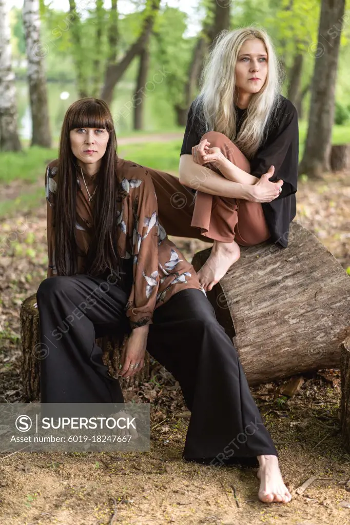 fashion twin girls posing against the background of a wooden lan