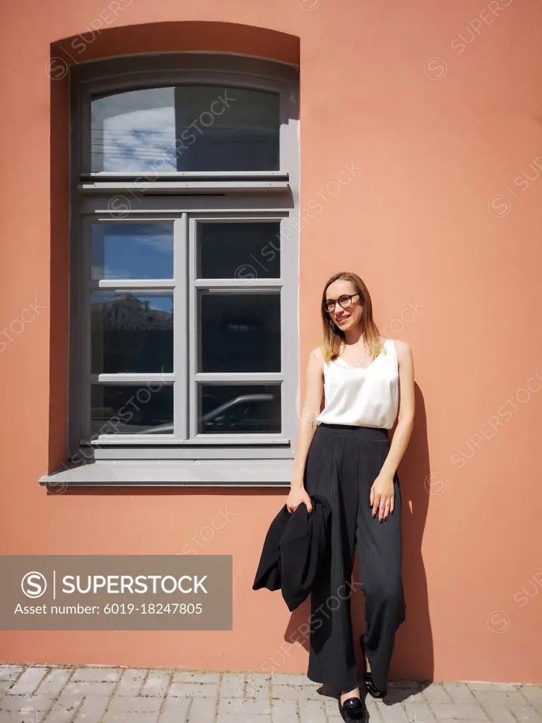 Portrait of a young smiling businesswoman opposite the orange wall and window
