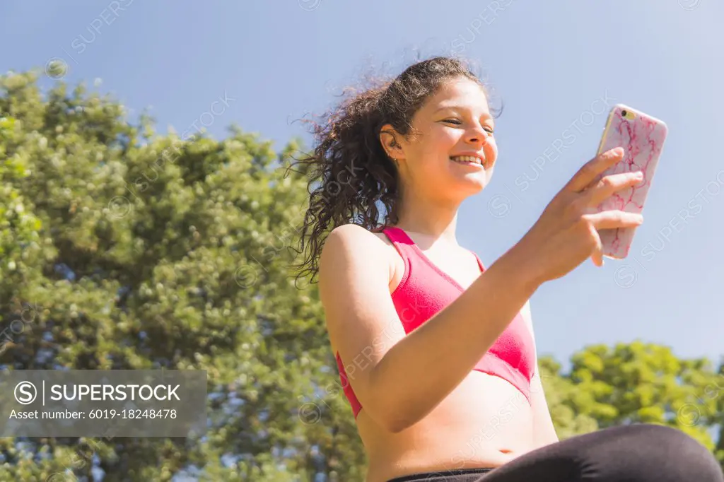 woman exercising looking at mobile in field