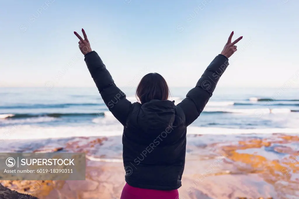 Woman wearing gym clothes looking at the ocean from the cliffs.