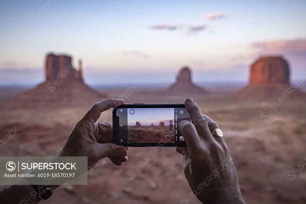 An adult male tourist takes a phone photo at Monument Valley, Arizona.