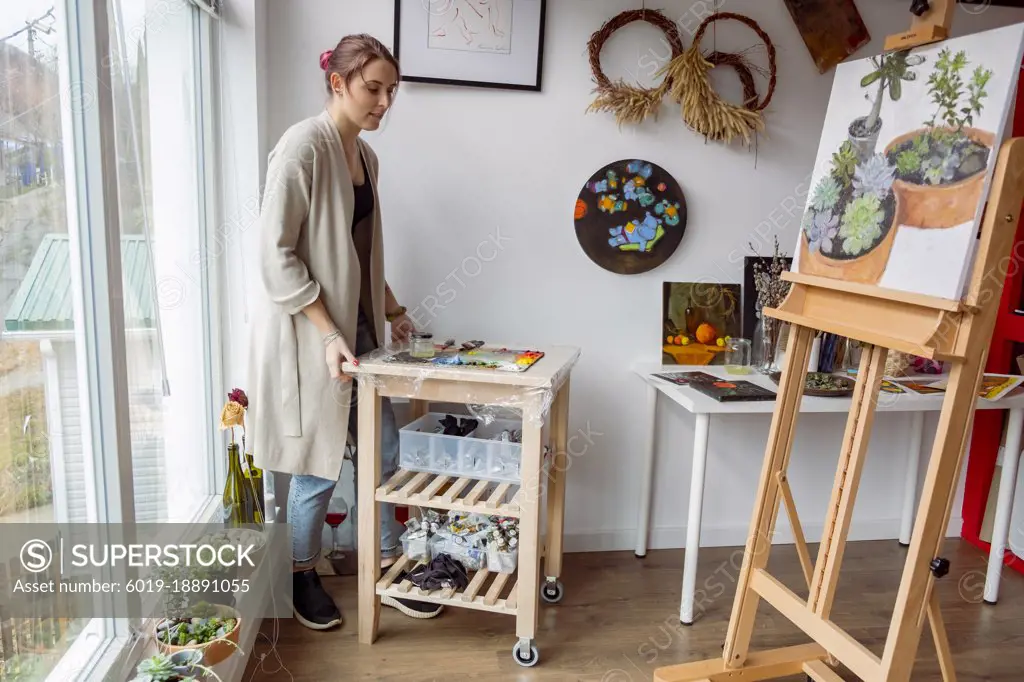 Woman artist moving table with oil paint