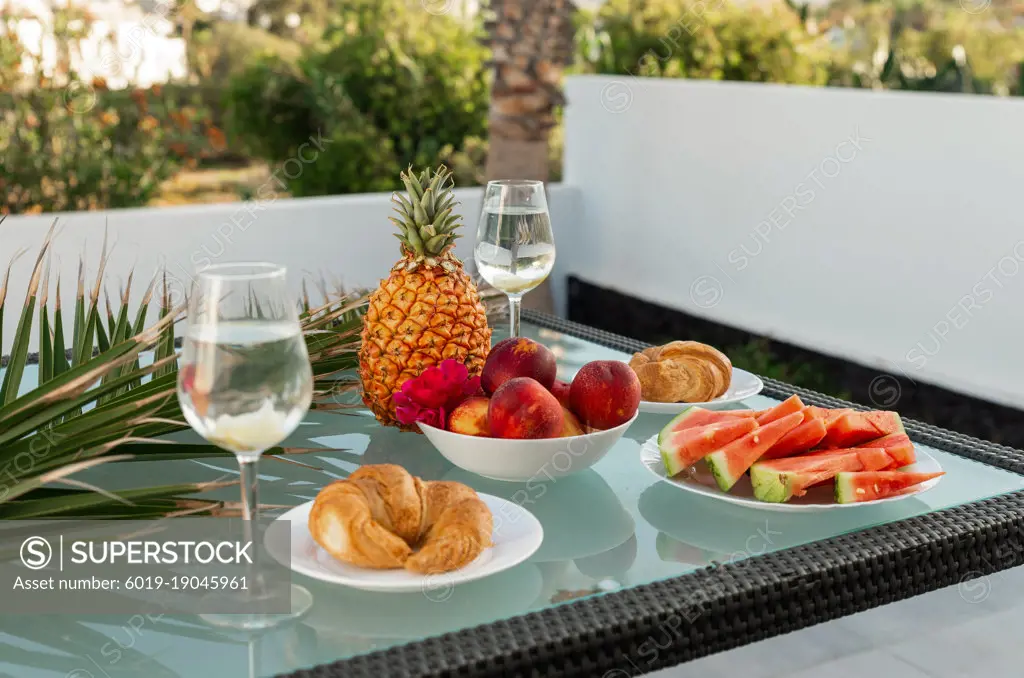 Tasty breakfast on glass table juice fruits with palm on background
