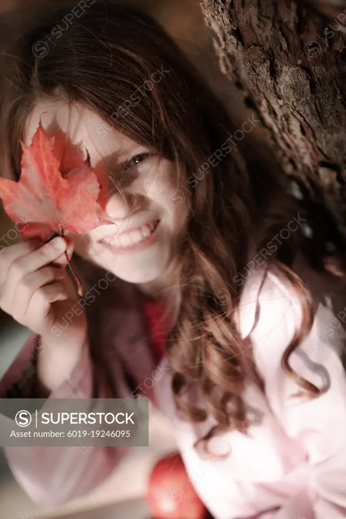 Portrait of a smiling girl in the park with autumn leaves.