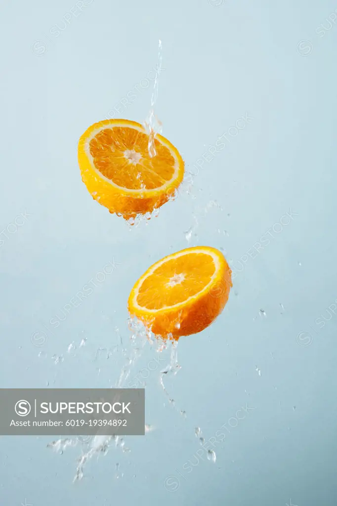 slices of oranges in water splash on a gray background, flying f