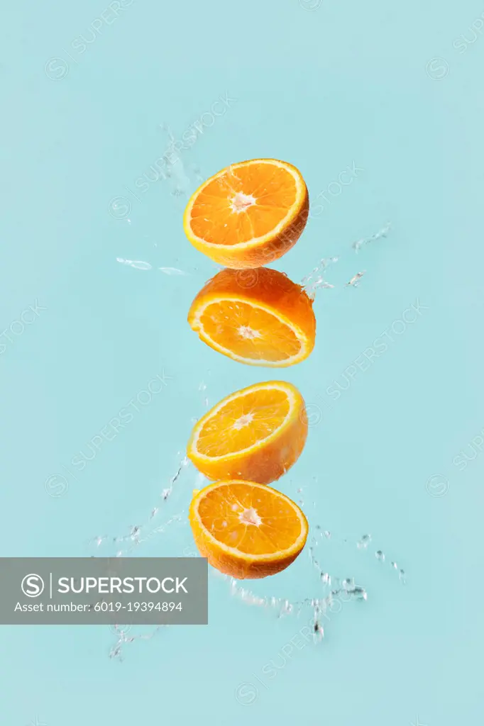 oranges fly on a blue background in water drops