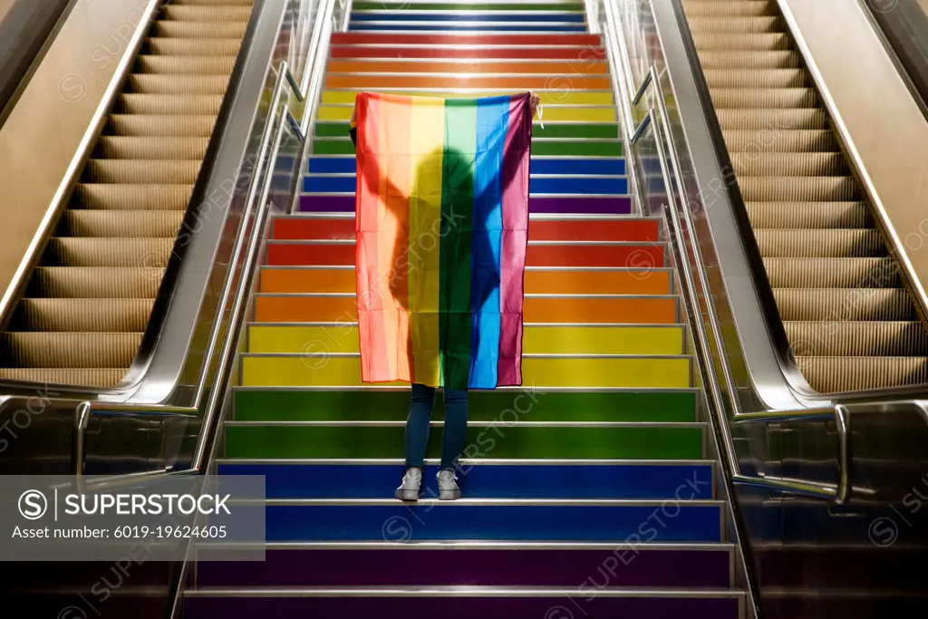 girl walking up the stairs with the lgtb flag on gay pride day.