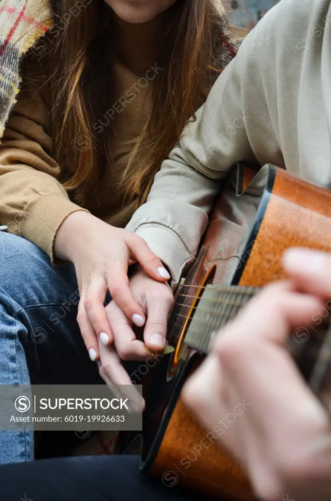 the hands of a girl and a boy on a guitar