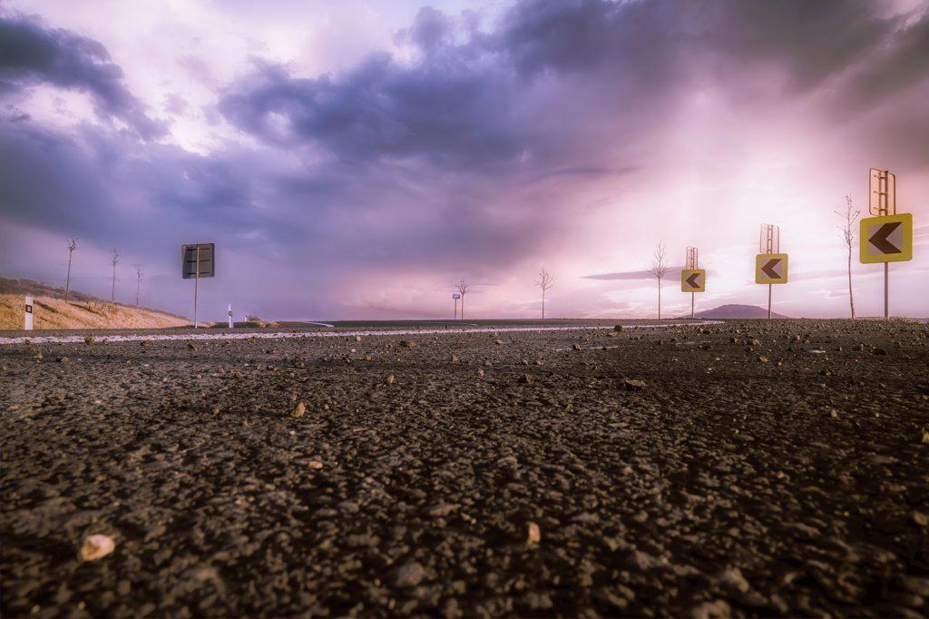 A asphalt road above a purple cloudy sky