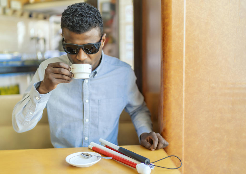 young blind african man having a coffee