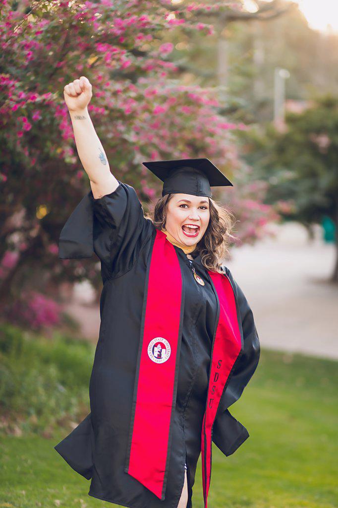 Woman excited to be graduating college, wearing a graduation gown/cap