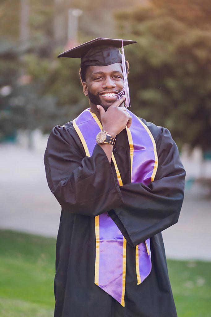 Man happy to be graduating college, wearing a graduation gown/cap
