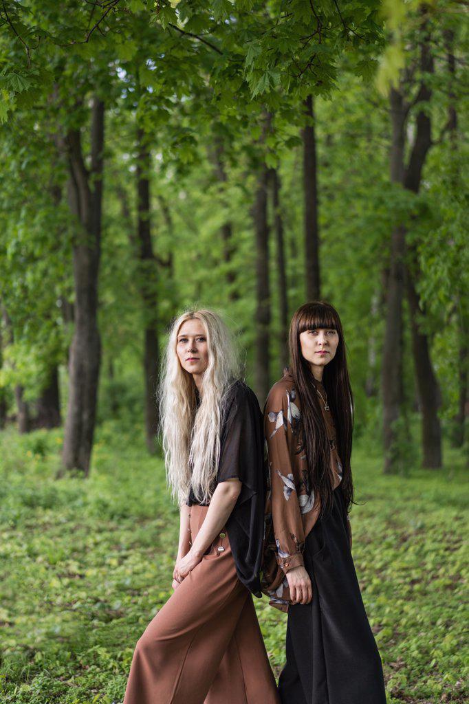 fashion twin girls posing against the background of a forest lan