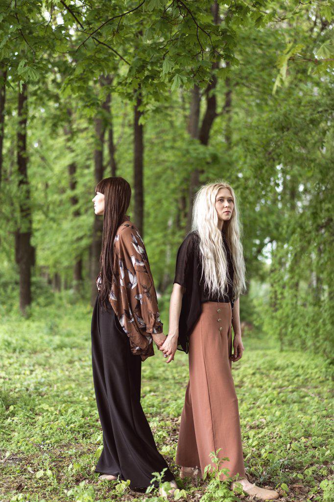 fashion twin girls posing against the background of a wooden lan