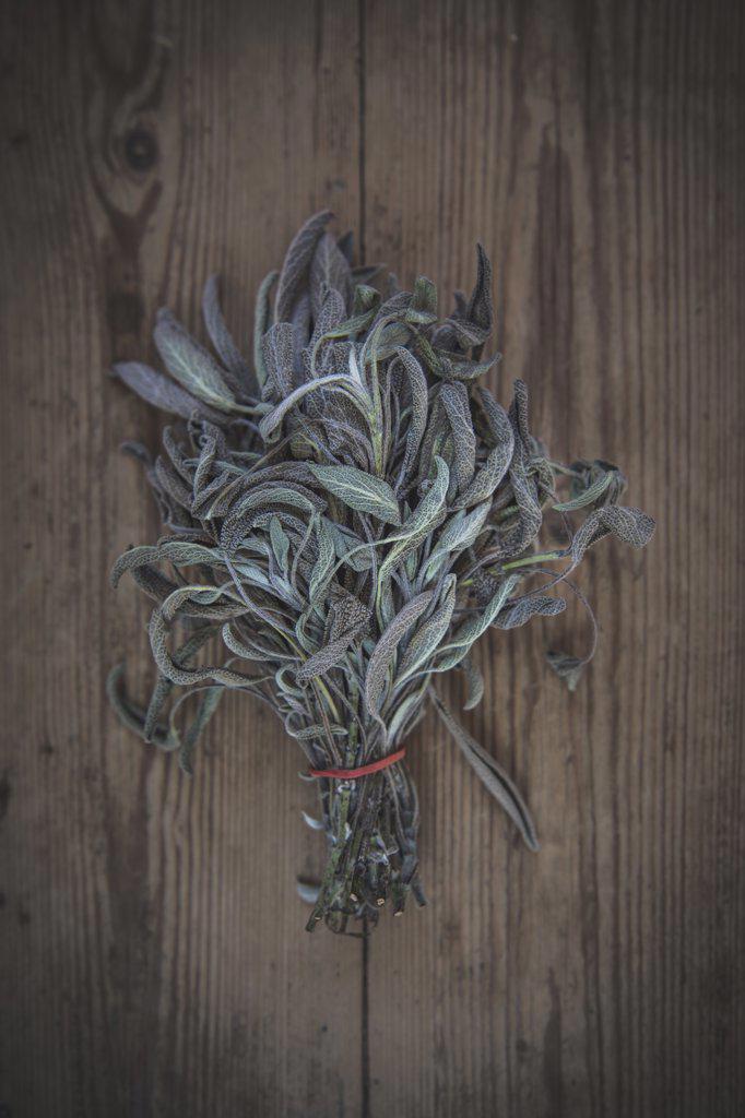 A bundle of sage lies on a wooden table