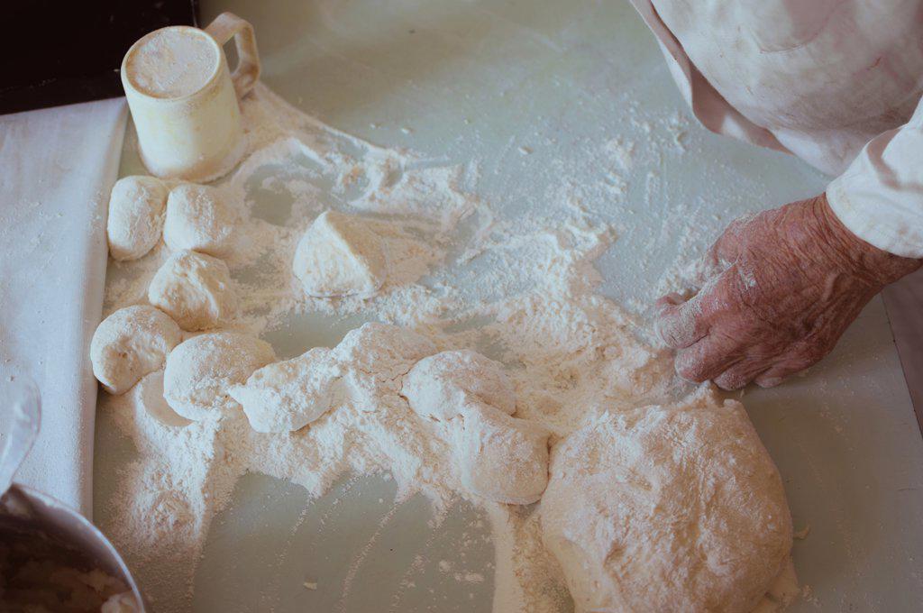 Old hands of 90-year-old woman make pies with potatoes out of dough