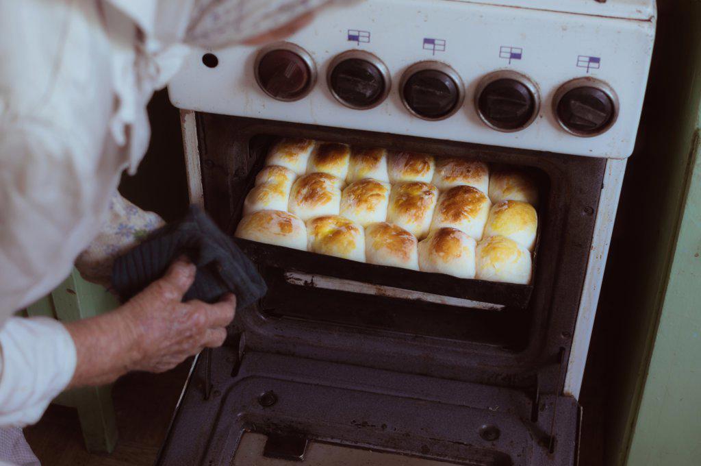 90-year-old woman takes out baking tray with baked ruddy pies