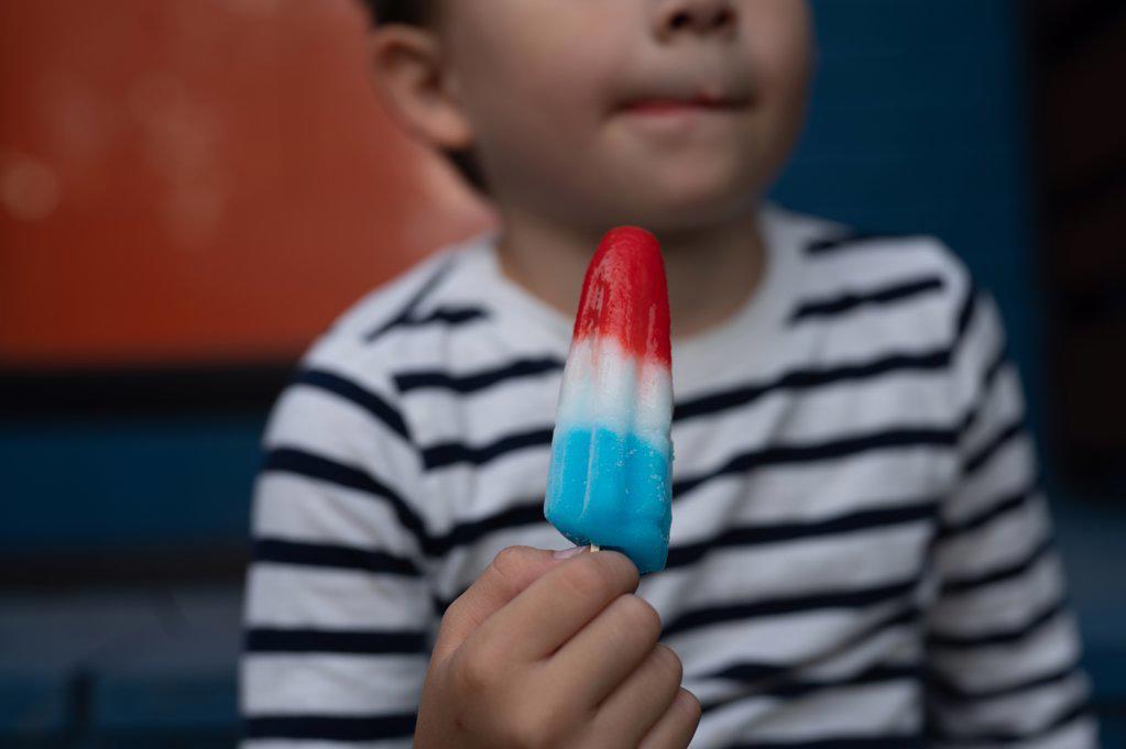 Young boy with melting popsicle on front porch
