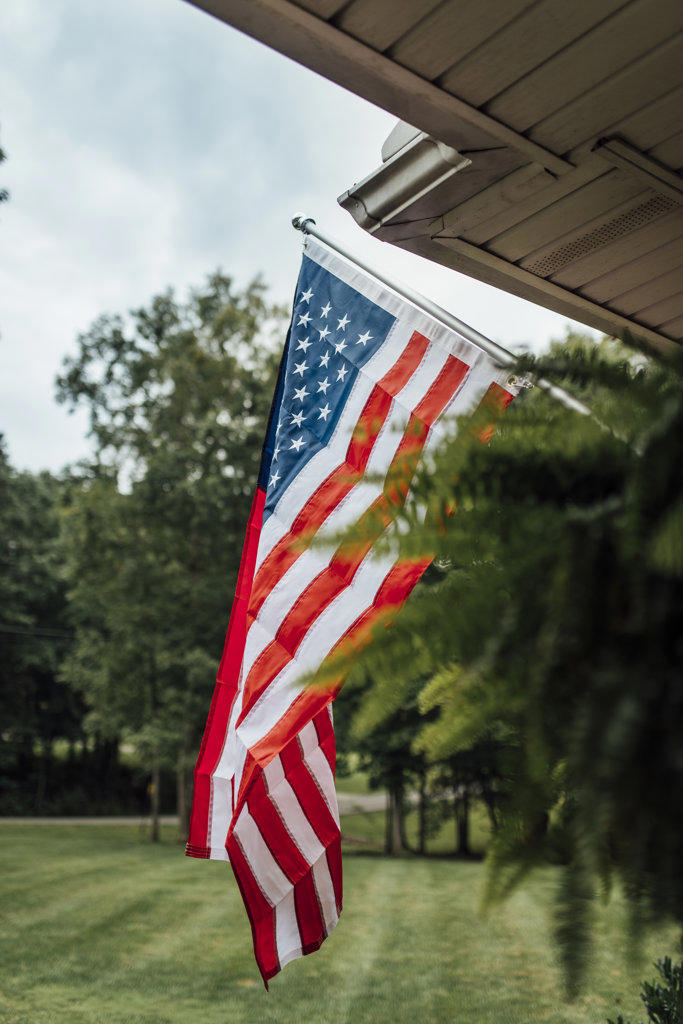 American flag on front porch with yard in background