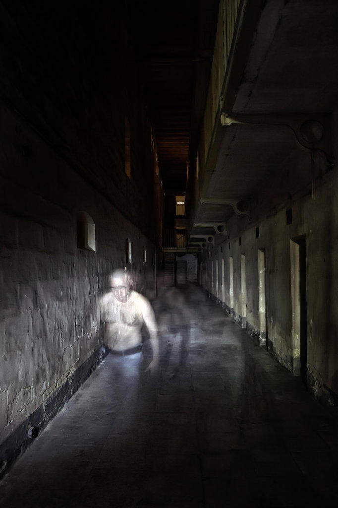 A Disturbed Inmate walks along a dark Asylum Corridor