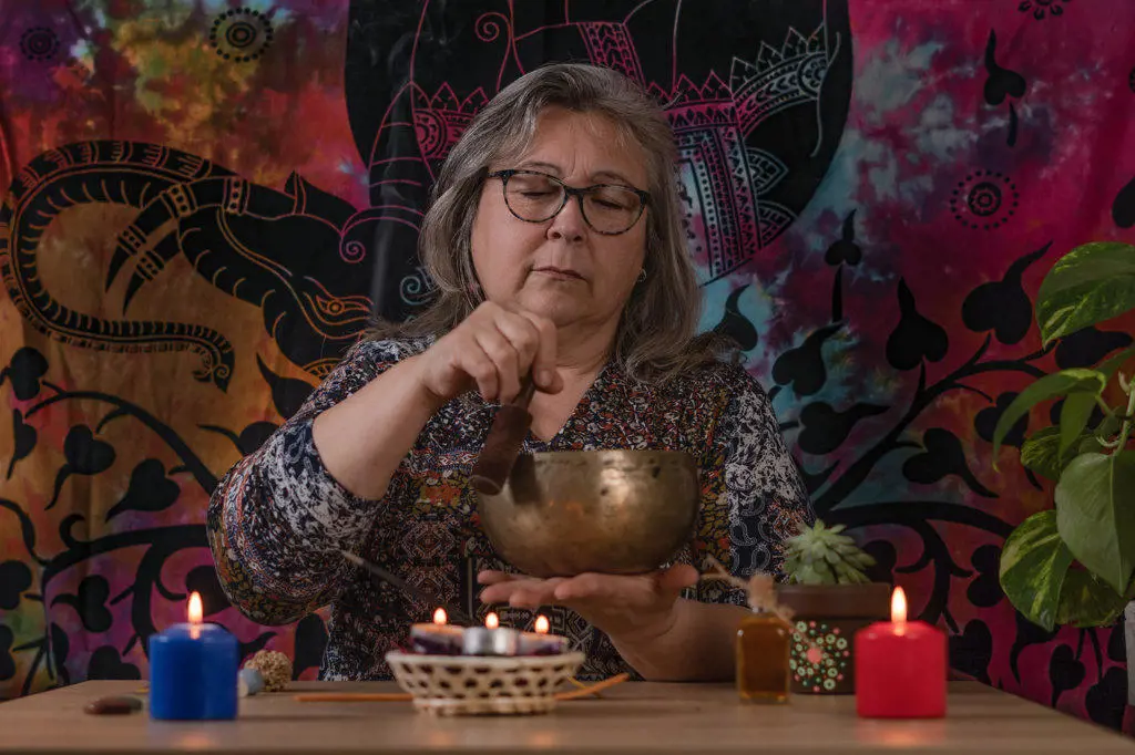 older woman ringing a Tibetan singing bowl