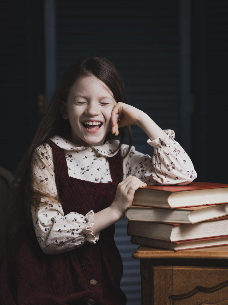 Portrait of a happy girl at the table with books.