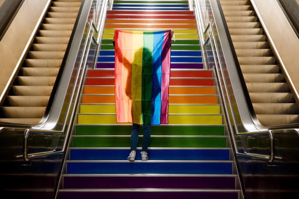 girl walking up the stairs with the lgtb flag on gay pride day.
