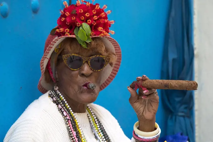 Portrait of older Cuban woman smoking two cigars in Havana, Cuba
