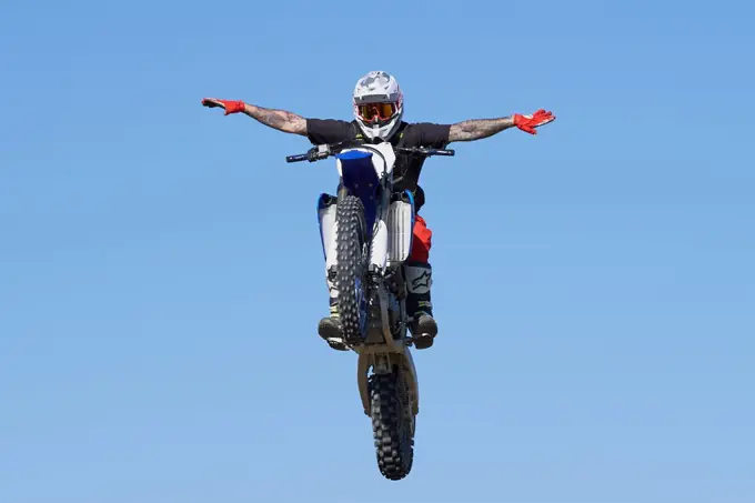 Side view of man performing stunt with motorcycle on motocross t