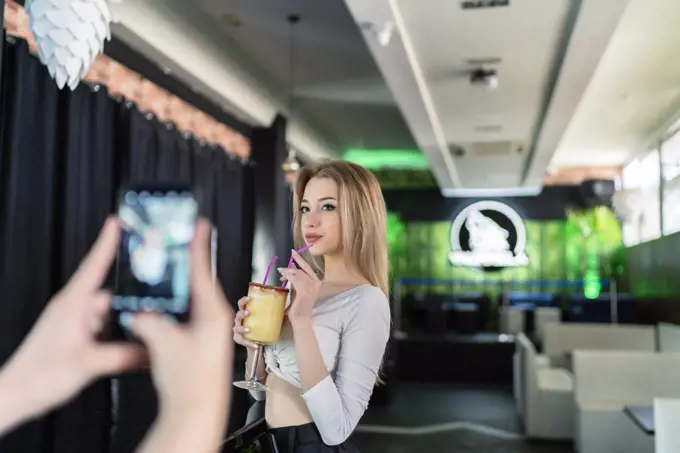 beautiful young blonde getting having a drink while being photographed