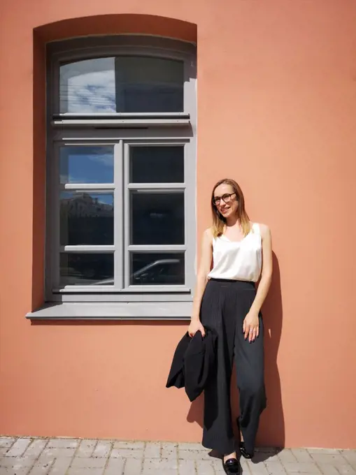 Portrait of a young smiling businesswoman opposite the orange wall and window