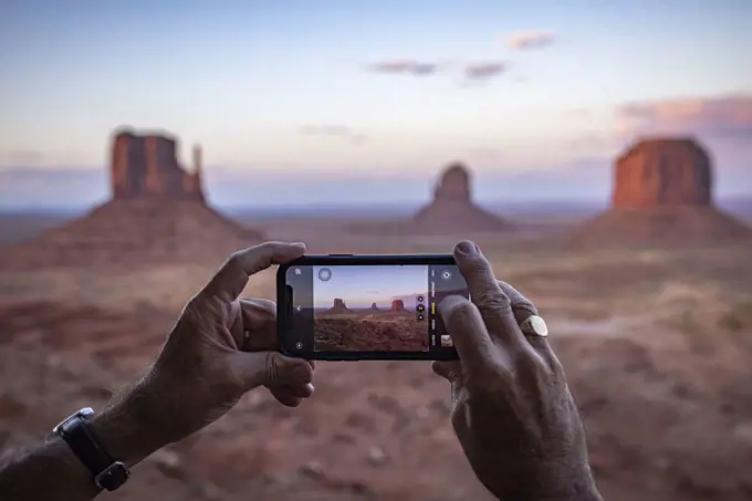 An adult male tourist takes a phone photo at Monument Valley, Arizona.