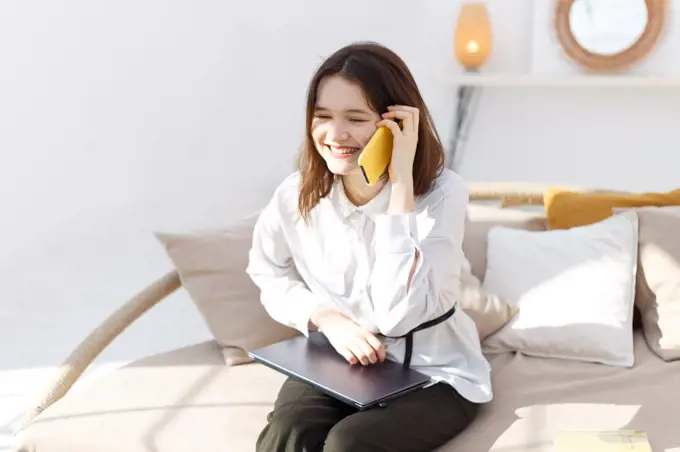 Young woman is talking on the smartphone from home office