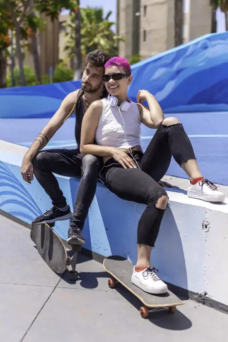 Young couple is sitting on the street park after skateboarding