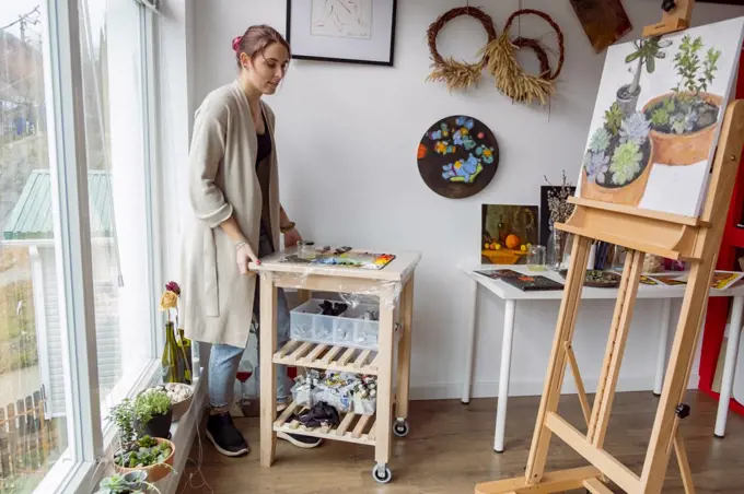 Woman artist moving table with oil paint