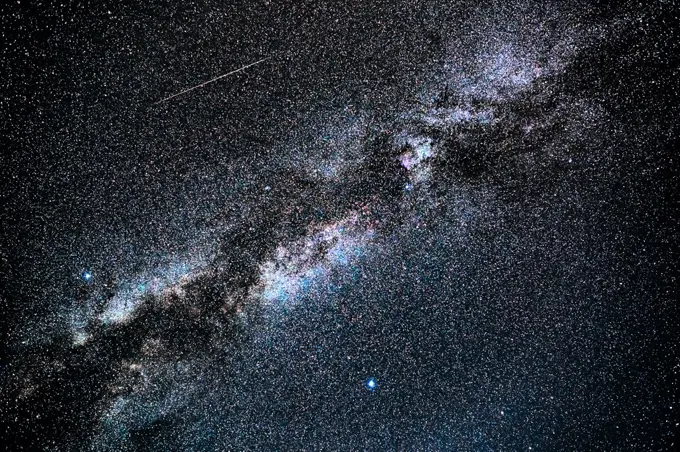 A shooting star steaks the sky next to the Milky Way