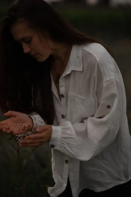Woman embracing, touching wild plants by hands.