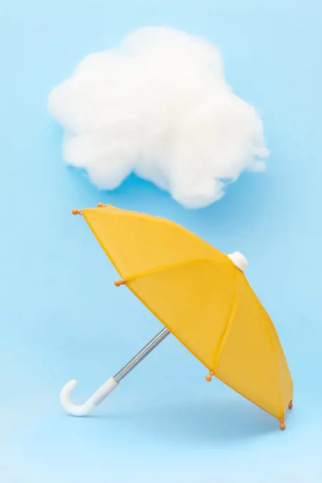 Yellow Toy Umbrella on Blue Background with White cloud